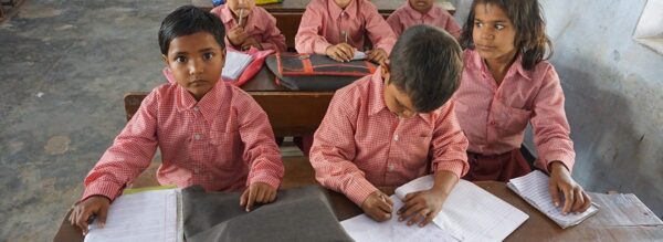 Intialaisia lapsia koulussa pulpettien ääressä