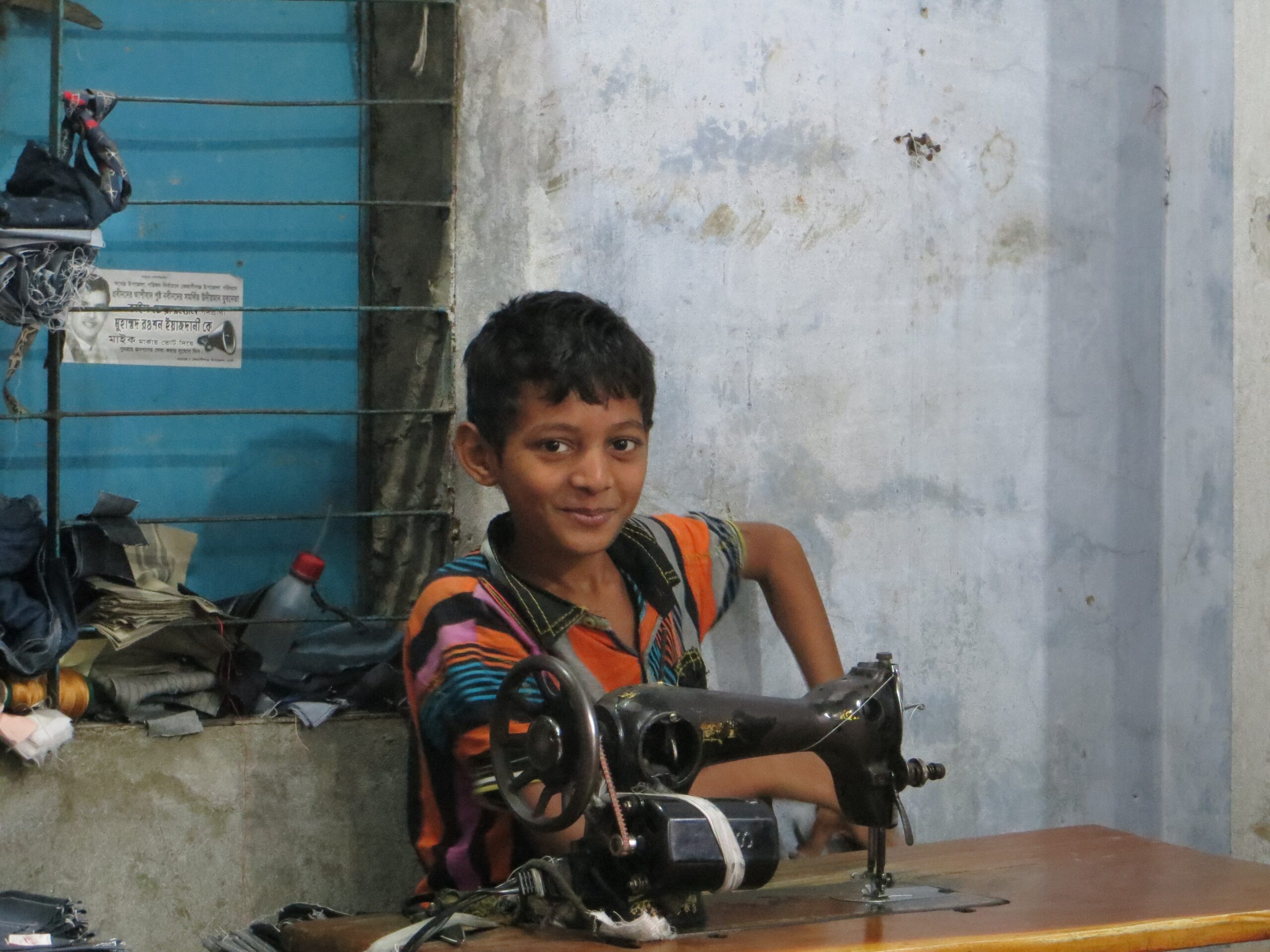 Bangladeshilainen poika ompelukoneen ääressä