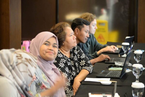 Indonesialaisia ammattiyhidstysaktiiveja kokouspöydän ääressä tietokoneineen