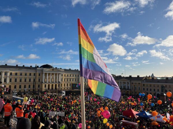 Sateenkaarilippu liehuu ammattiliittojen järjestämässä STOP Nyt -tapahtumassa Helsingin Senaatintorilla helmikuussa 2024