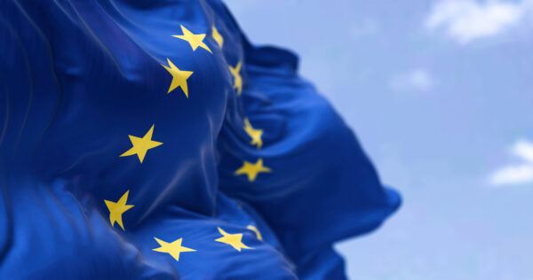 EU:n lippu liehuu lähikuvassa sinistä taivasta vasten