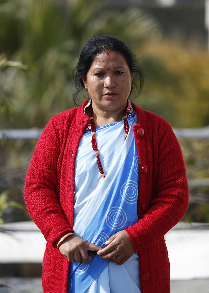 Nepalin terveysvapaaehtoisten järjestön HEVONin puheenjohtaja Basanti Maharjan työasussaan vaaleansinisessä sarissa. Päällä punainen villatakki.