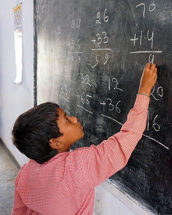 Lapsi laskee matematiikkaa liitutaululle